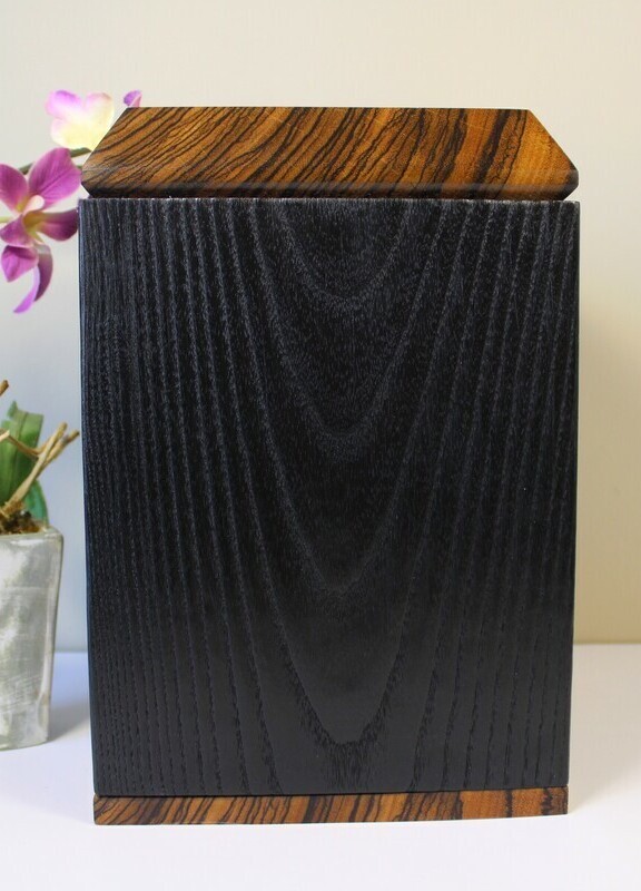 Left side view of a charred ash and zebrawood wooden cremation urn
