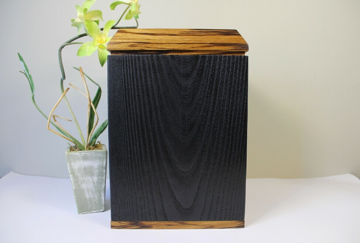 Front view of a charred ash and zebrawood wooden cremation urn
