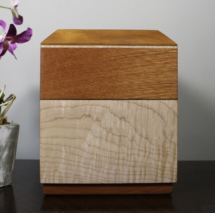 Front view of a cherry, mahogany and curly maple wooden cremation urn