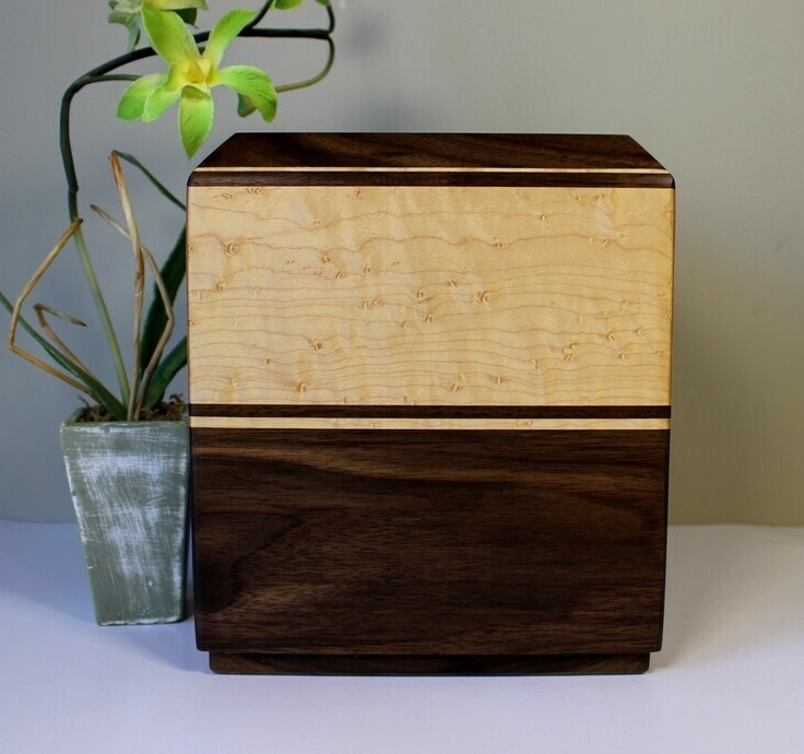 Front view of a black walnut and bird's eye maple wooden cremation urn