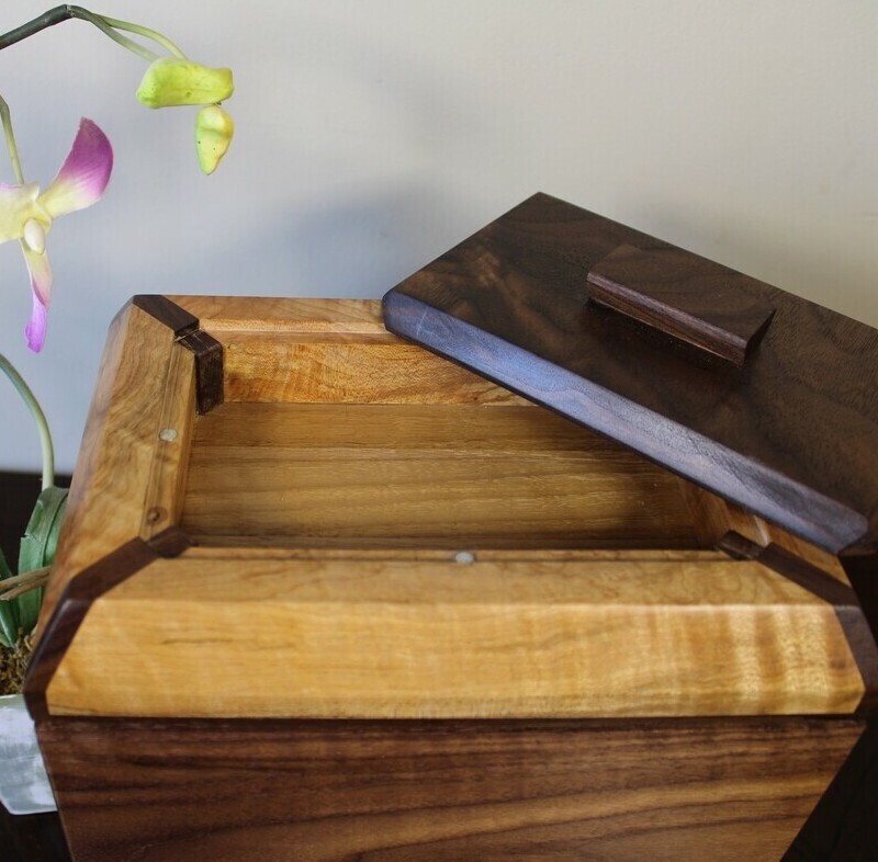 Receptacle view of a black walnut and figured maple wooden cremation urn