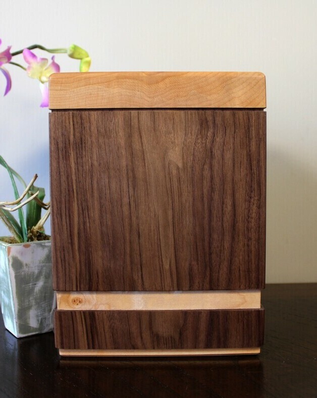 Back view of a black walnut and quilted maple wooden cremation urn