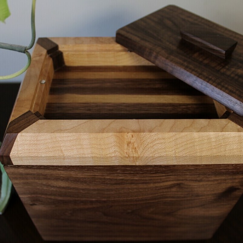 Compartment view of a black walnut and figured maple wooden cremation urn