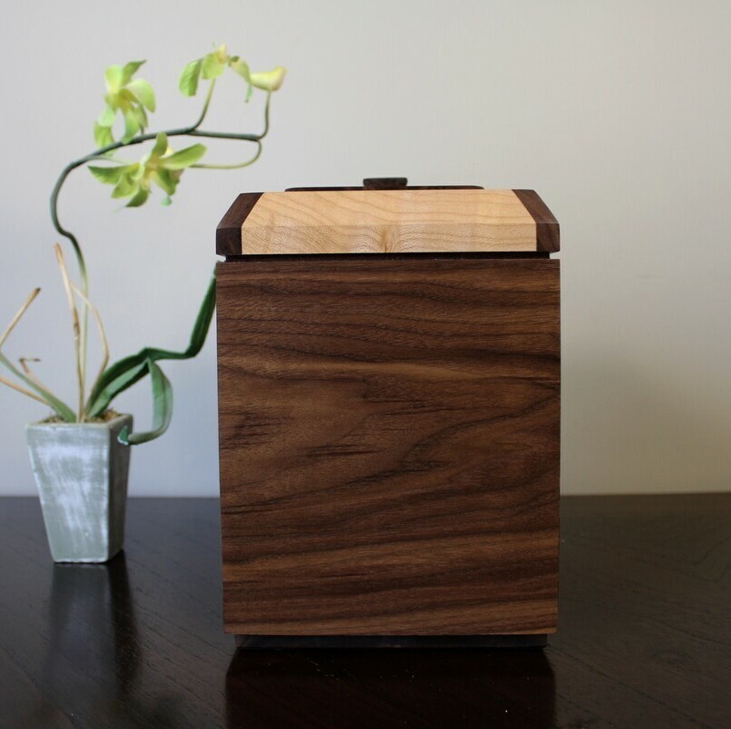 Right side view of a black walnut and figured maple wooden cremation urn with integrated compartment 