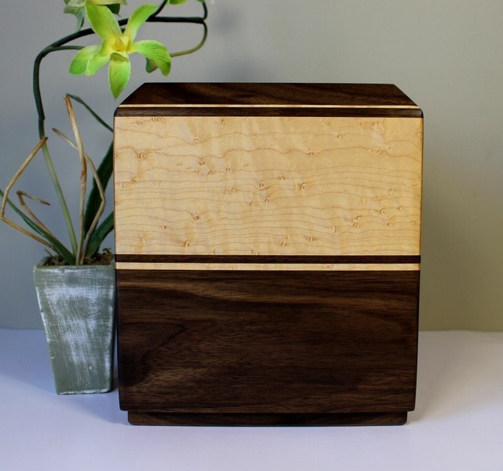 Front view of a black walnut and bird's eye maple wooden cremation urn