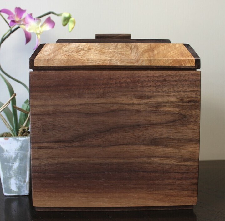 Back view of a black walnut and figured maple wooden cremation urn with receptacle