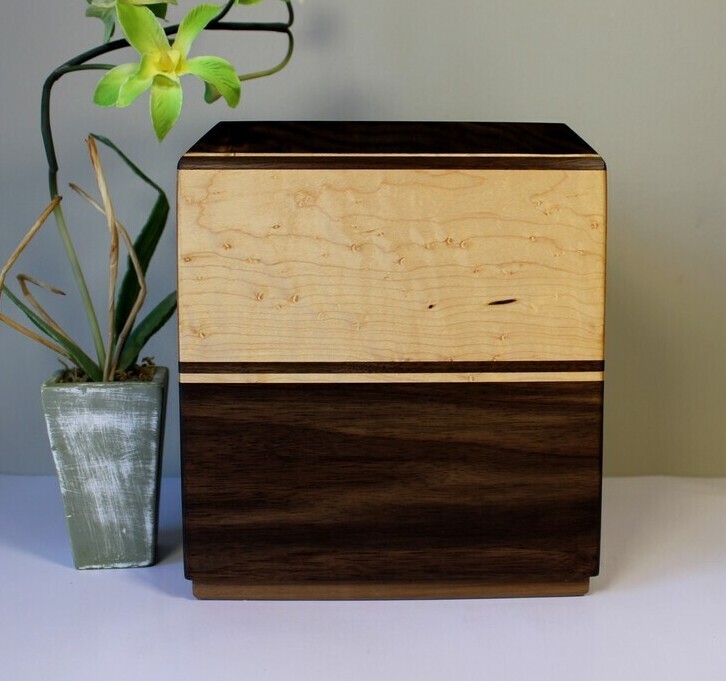 Left side view of a black walnut and bird's eye maple wooden cremation urn