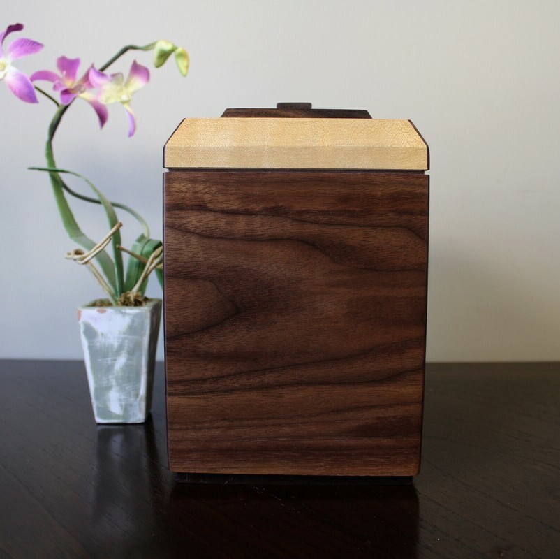Right side view of a black walnut and figured maple wooden cremation urn with keepsake compartment