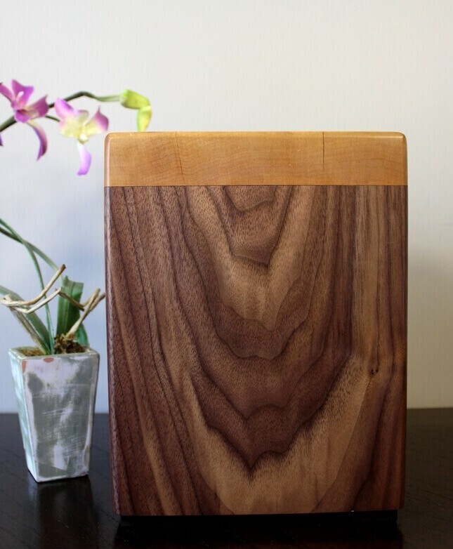 Left side view of a black walnut and figured maple wooden cremation urn