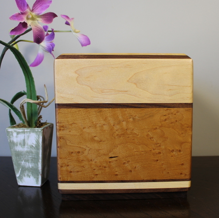 Left side view of a light maple and torrefied bird's eye maple wooden cremation urn