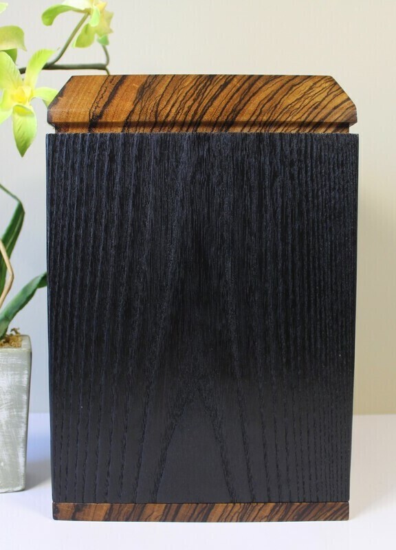 Left side view of a charred ash and zebrawood wooden cremation urn