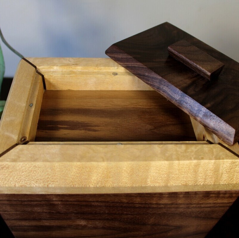 Compartment view of a black walnut and figured maple wooden cremation urn 