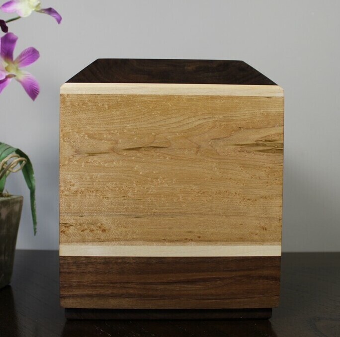 Front view of a bird's eye maple and black walnut wooden cremation urn