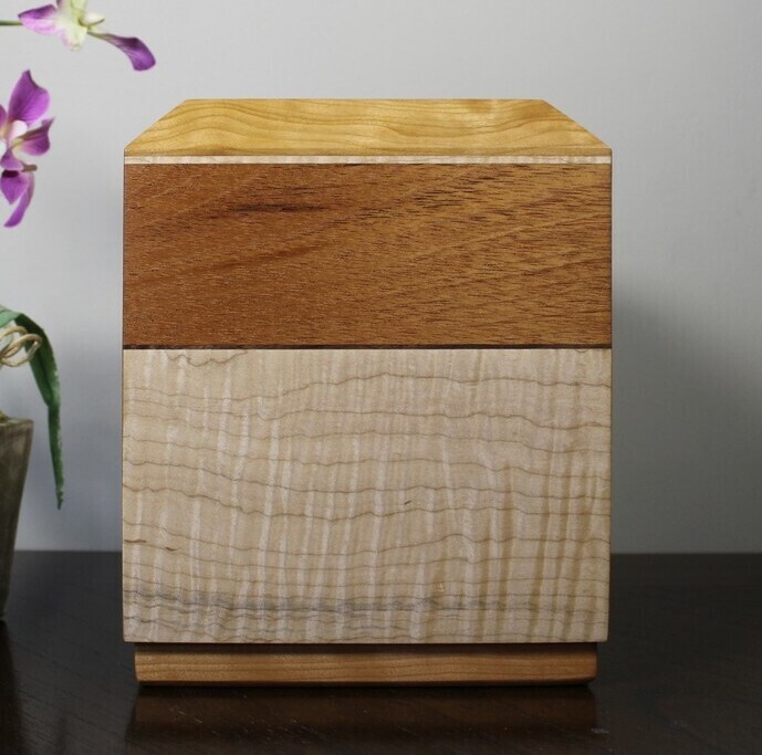 Left side view of a cherry, mahogany and curly maple wooden cremation urn
