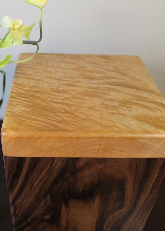 Close up view of a black walnut and flamed maple wooden cremation urn