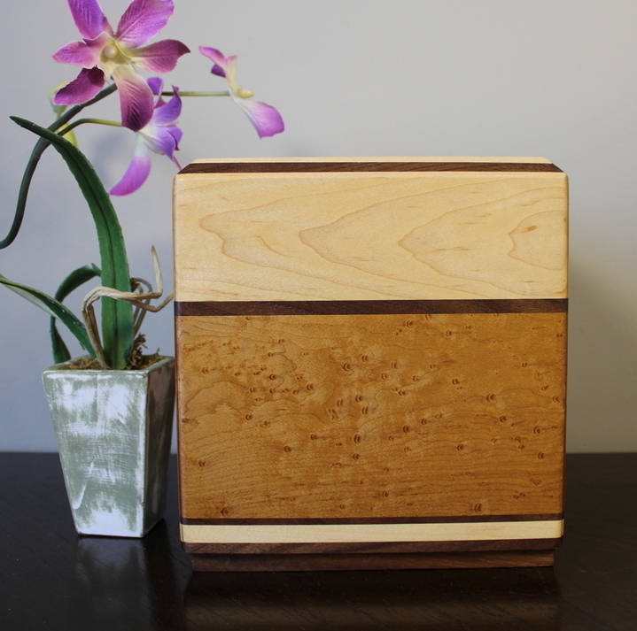Front view of a light maple and torrefied bird's eye maple wooden cremation urn