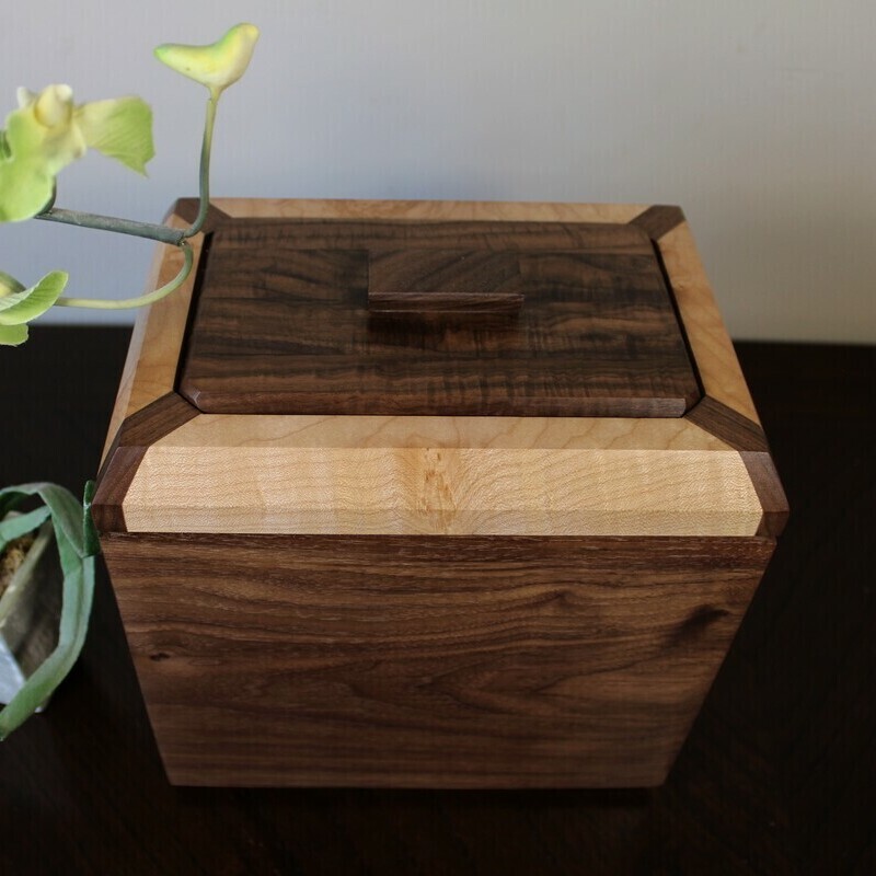 Top view of a black walnut and figured maple wooden cremation urn with integrated compartment 